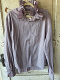 A long-sleeve button-up shirt with a pink and blue gingham check pattern and a ruffled collar, hanging on a wooden hanger against a distressed white wooden door.